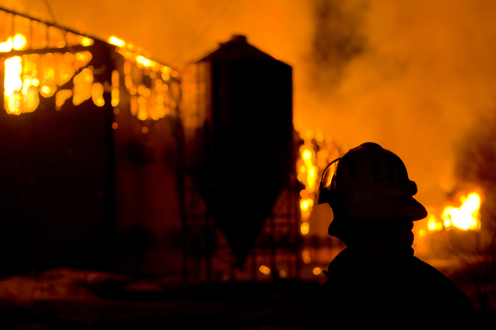 silhouette of a firefighter watching a barn burning